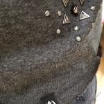 Studs, tag, & raw edge of the cold-shoulder sweater